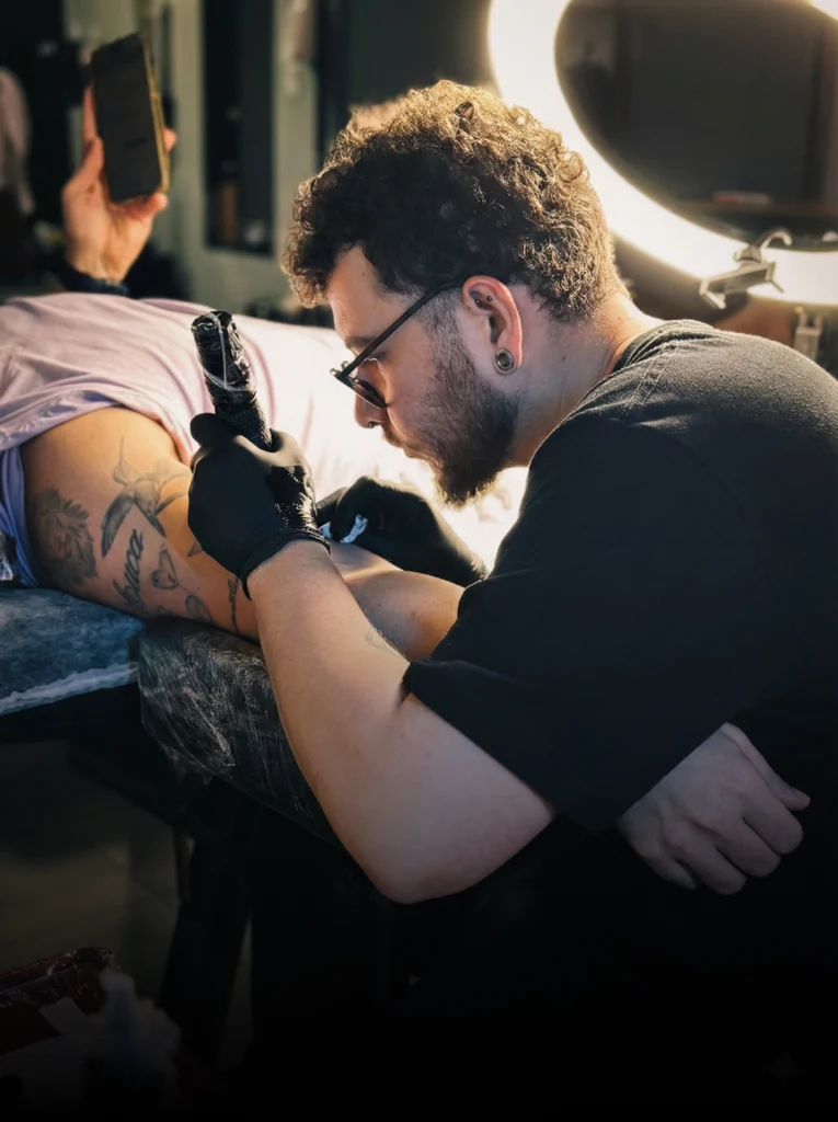 Artista realizando cobertura de tatuagem